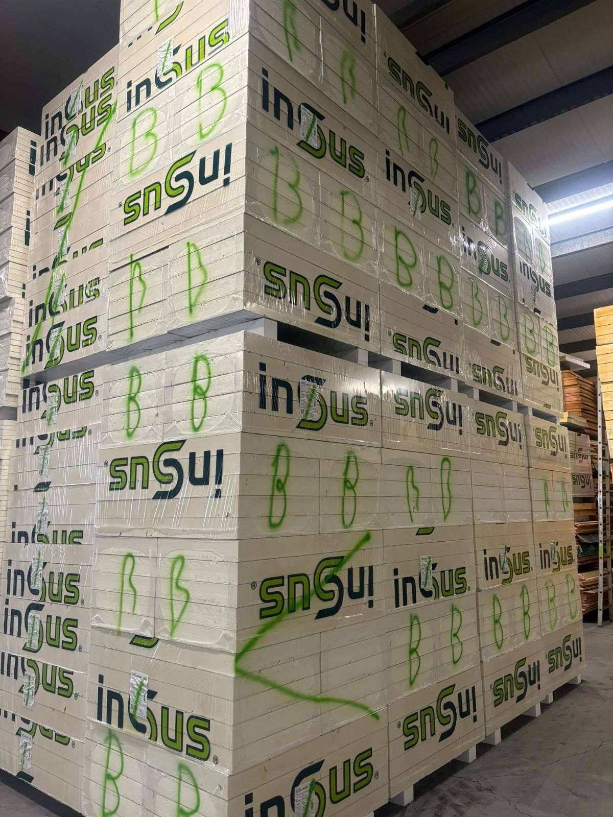 Een hoge stapel PIR isolatieplaten, gemarkeerd met een groene B