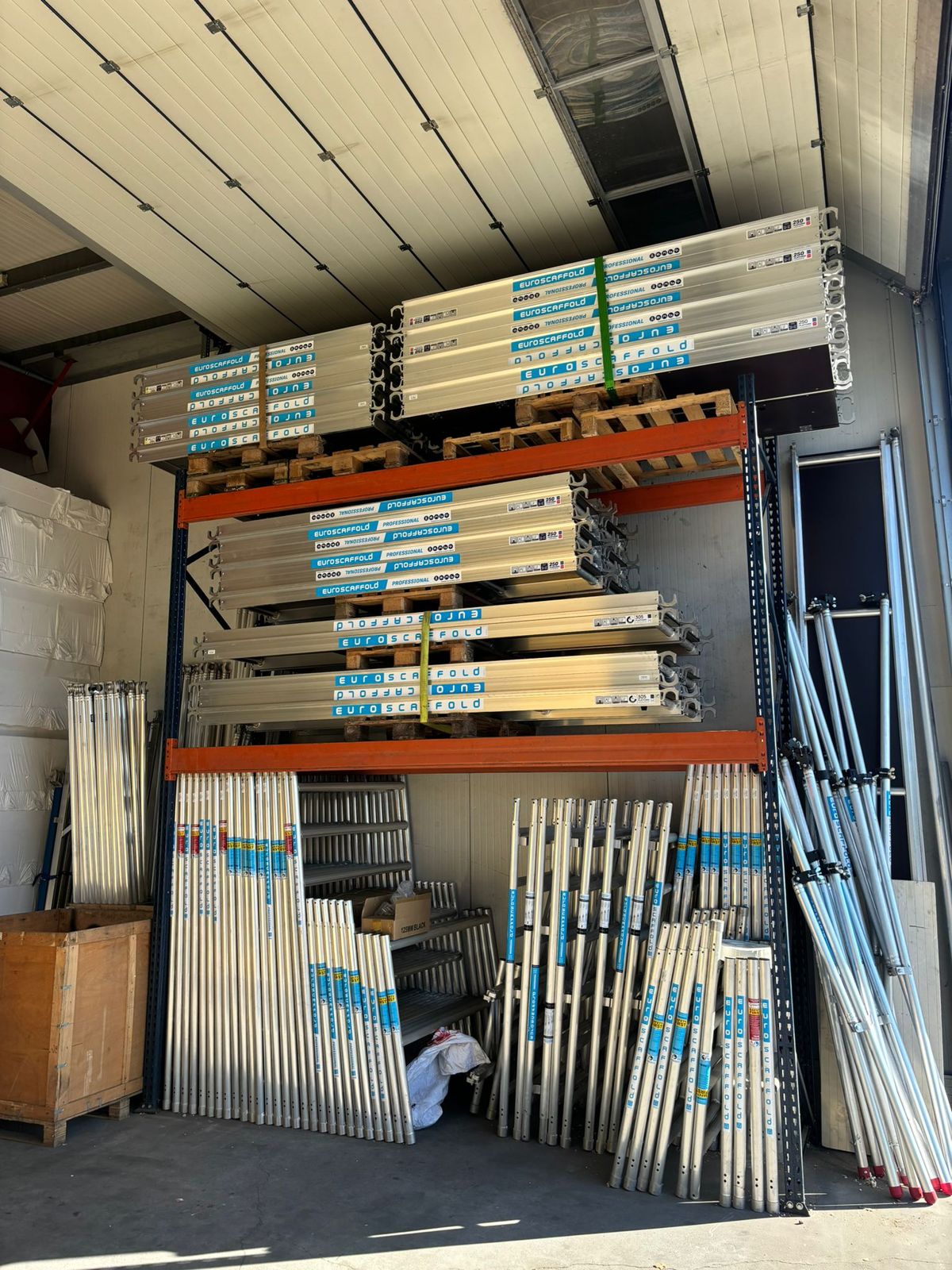 Palletstellingen met platen en profielen achter een roldeur